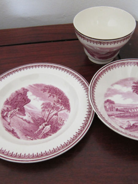 Victorian-era Wedgwood Etruria of dark fuschia landscape and people images. Set includes handle-less cup which was used to pour tea into the deep saucer and from which users sipped their tea. The plate was used either for biscuits or for a place to set down the deep-bowled saucer.